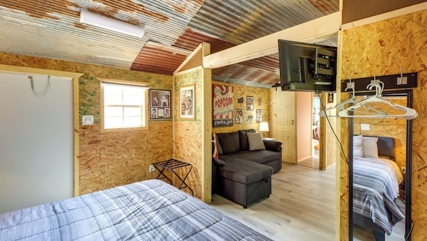 Ett rum med en säng, en soffa, en tv och en vägg som är klädd med träpanel.
