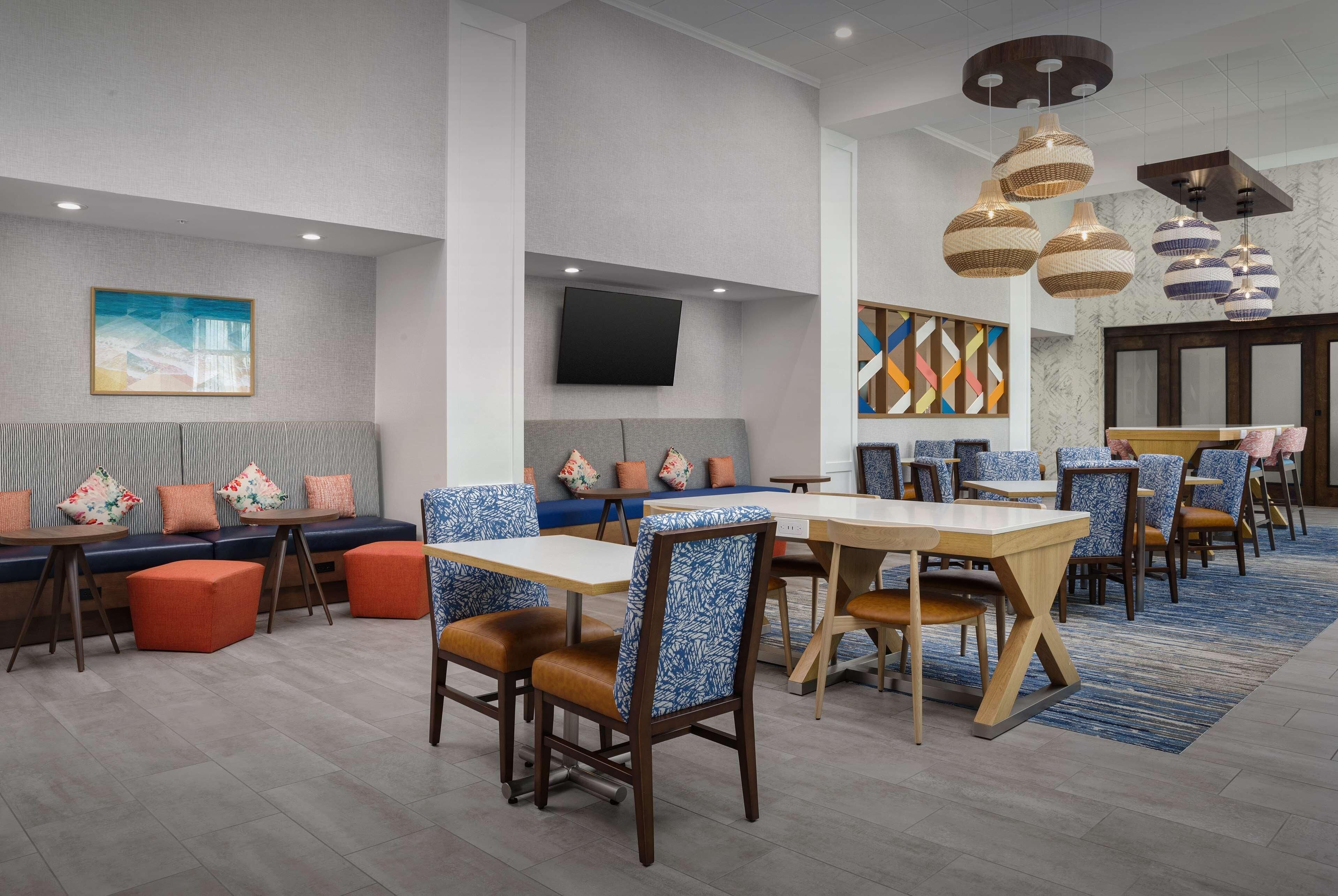 A modern dining area with booths and tables, a flat-screen TV, and decorative wall art.