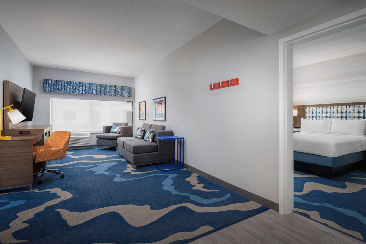 A hotel room with a desk, chair, sofa, and bed.