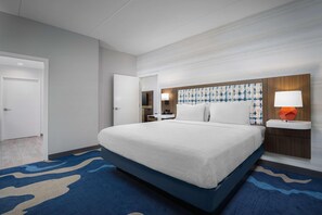 A modern hotel room with a large bed, a nightstand with a lamp, and a bathroom visible through an open door. - Hampton Inn And Suites By Hilton Naples South (Naples)