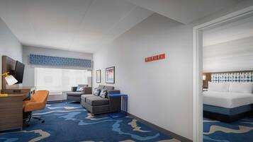 Una habitación de hotel con escritorio, silla, sofá y cama.