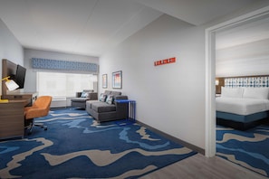 A hotel room with a desk, chair, sofa, and bed. - Hampton Inn And Suites By Hilton Naples South (Naples)