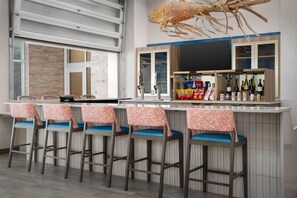 A bar area with a seafood-themed decoration, bar stools with patterned covers, and a variety of snacks and beverages. - Hampton Inn And Suites By Hilton Naples South (Naples)
