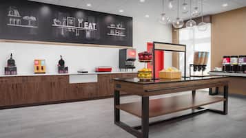 Un café moderne avec un intérieur contemporain, un mur recouvert d’un tableau noir, un coin pour préparer des jus et un bar où l’on peut prendre le petit-déjeuner.