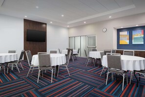 A conference room with round tables, chairs, a flat-screen TV, and a colorful carpet. - Hampton Inn And Suites By Hilton Naples South (Naples)