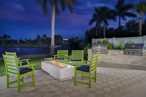 An outdoor patio with green chairs, a fire pit, and a barbecue grill. - Hampton Inn And Suites By Hilton Naples South (Naples)
