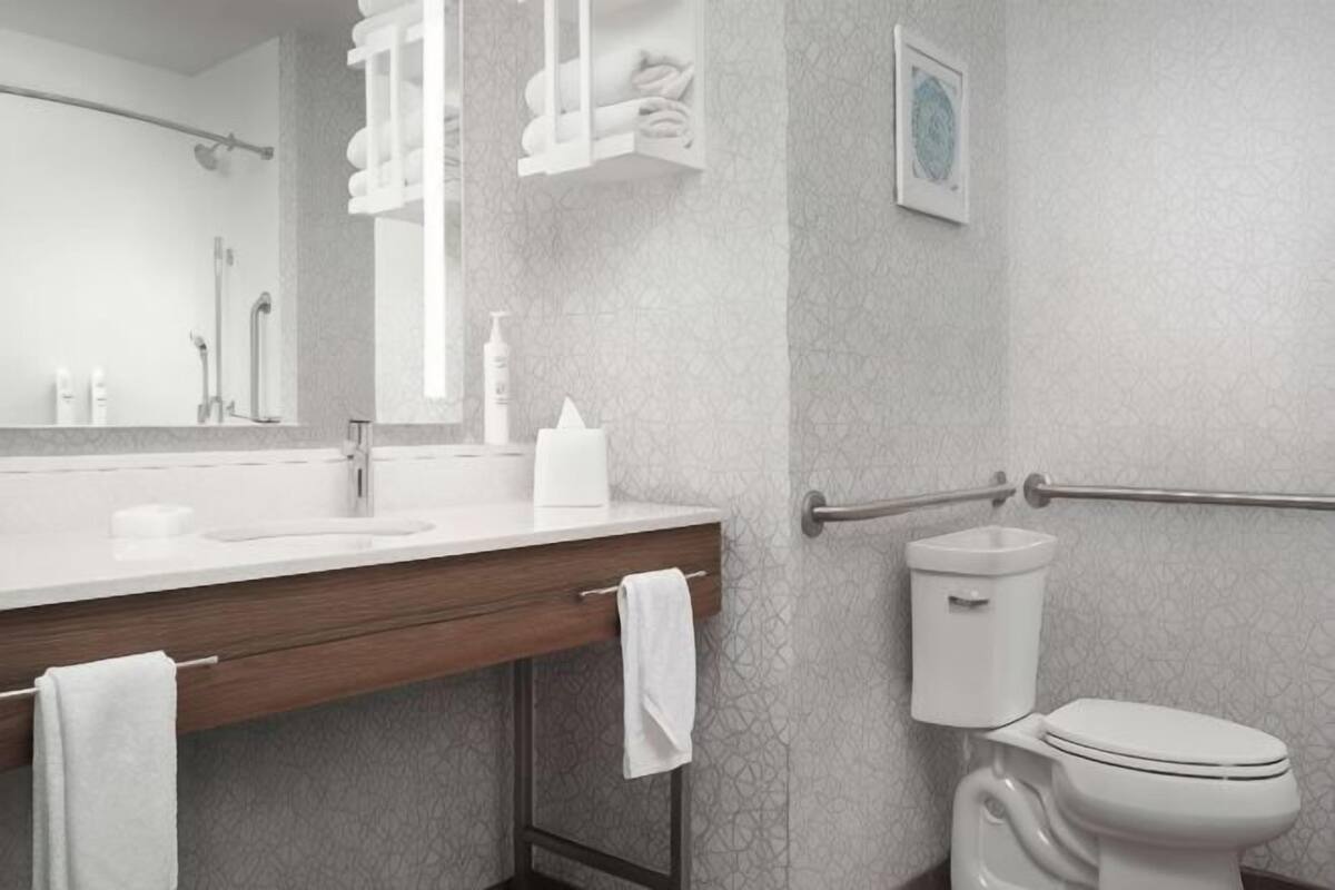 A bathroom with a white sink, mirror, towel rack, and toilet.