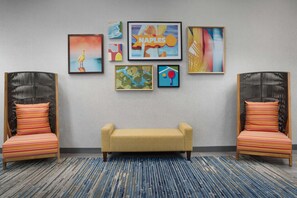 A room with a sofa, two striped chairs, and a patterned carpet. - Hampton Inn And Suites By Hilton Naples South (Naples)