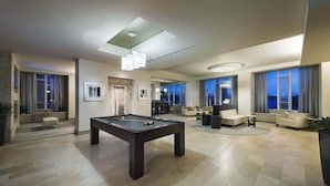 A modern living room with a pool table, a sofa, and a dining area.