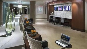 A modern lobby with a reception desk, seating area, and a laptop on a table.