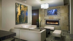 A modern living room with a sectional sofa, a fireplace, a flat-screen TV, and a large abstract painting. - Boston Harbor 1 BR | Desk+Wi-Fi | Kitchen (Boston)