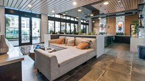 A modern lobby with a sofa, a reception desk, and a kitchen area. - Designer Suites in Menlo Park | Work & Relax (Menlo Park)