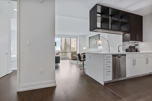 A modern kitchen with white cabinetry, a built-in dishwasher, and a large island.