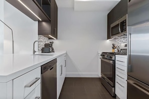 A modern kitchen with white cabinetry, stainless steel appliances, and a tiled backsplash.