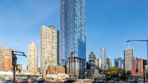 Un paysage urbain caractérisé par un gratte-ciel moderne imposant, plusieurs immeubles de taille moyenne, et un mélange de bâtiments commerciaux et résidentiels.