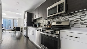 A modern kitchen with dark cabinets, stainless steel appliances, and a tiled backsplash.