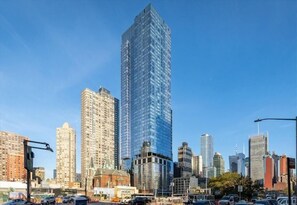 A cityscape with a prominent modern skyscraper, several mid-rise buildings, and a mix of commercial and residential structures.