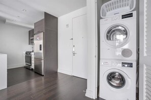 A laundry room with stacked washers and dryers, a microwave, and a refrigerator.