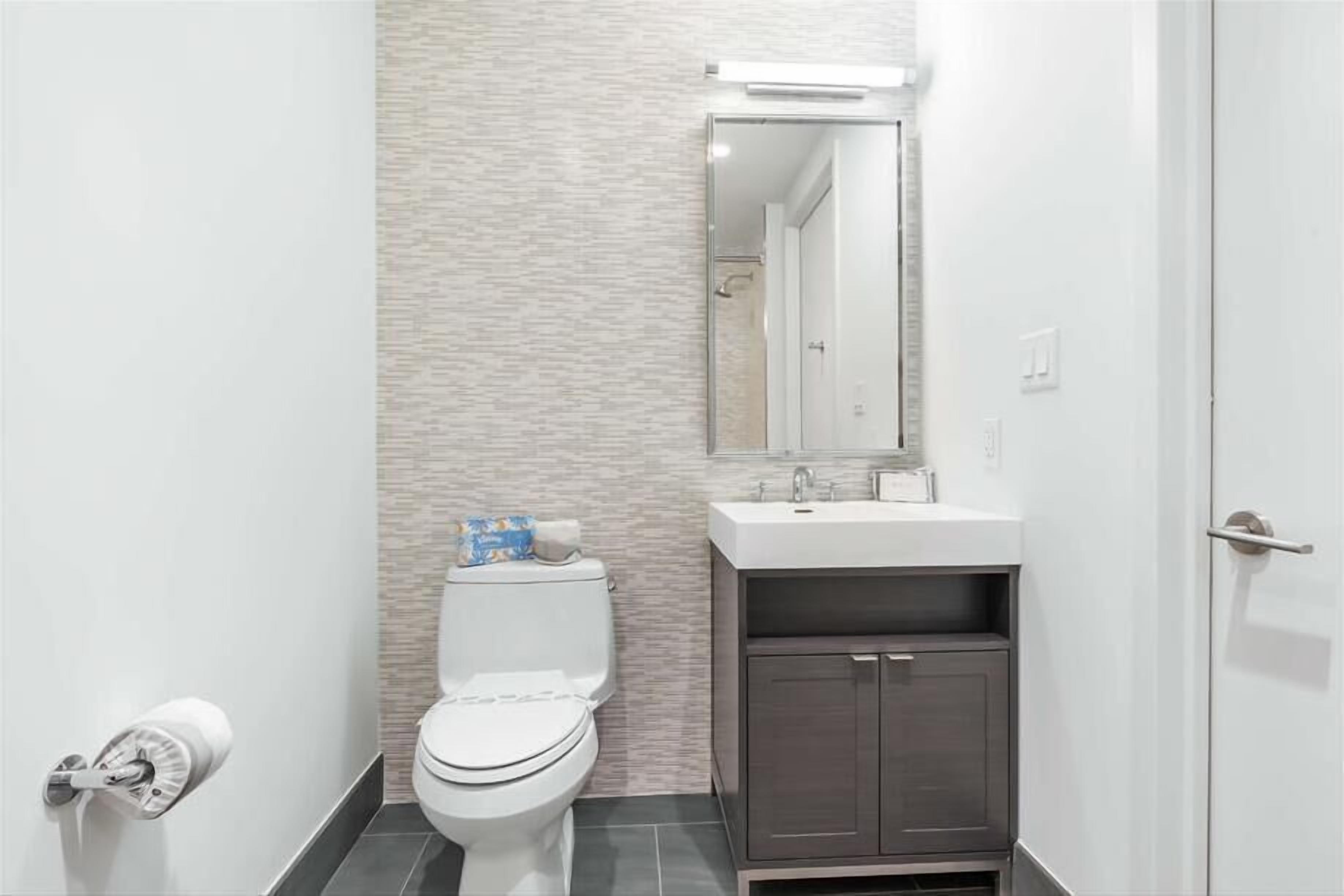 Un baño moderno con inodoro, lavamanos y mueble.