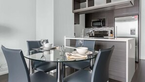 Eine moderne Küche mit Mikrowelle, Kühlschrank und einem Glastisch mit Stühlen.