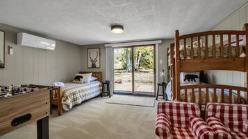 A room with a bed, a futon, a foosball table, and a bunk bed.