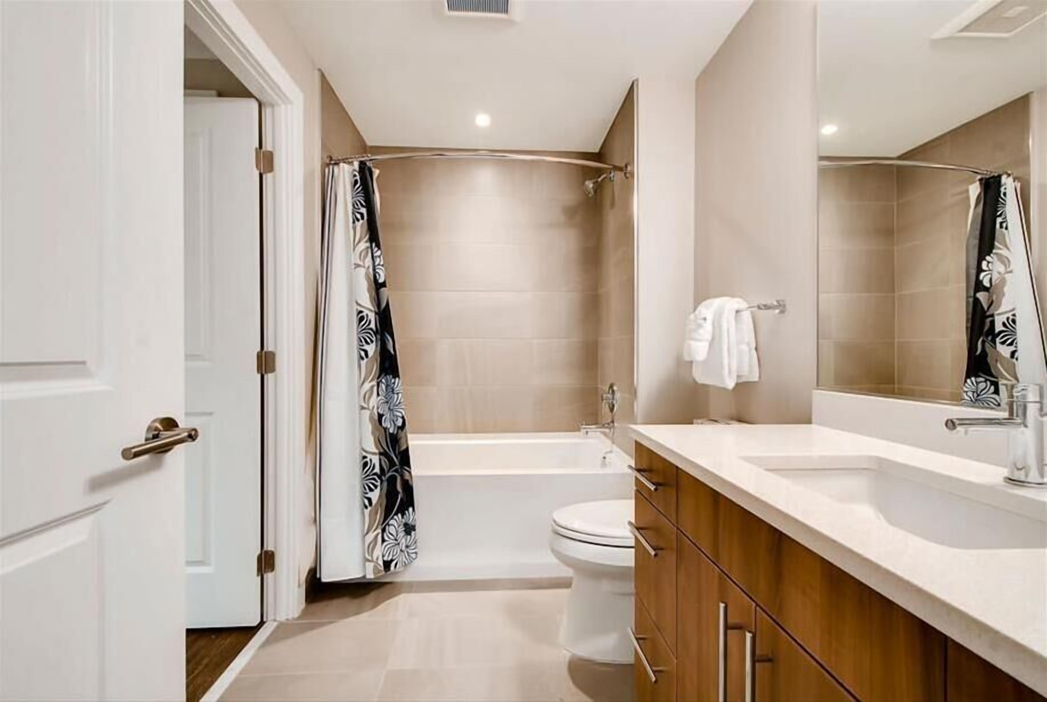 A modern bathroom with a bathtub, toilet, and vanity with a mirror.