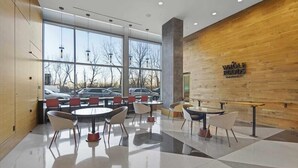 Un espacio interior moderno con una pared de madera, un letrero que dice “WHOLE FOODS MARKET” y una zona de estar con mesas y sillas.
