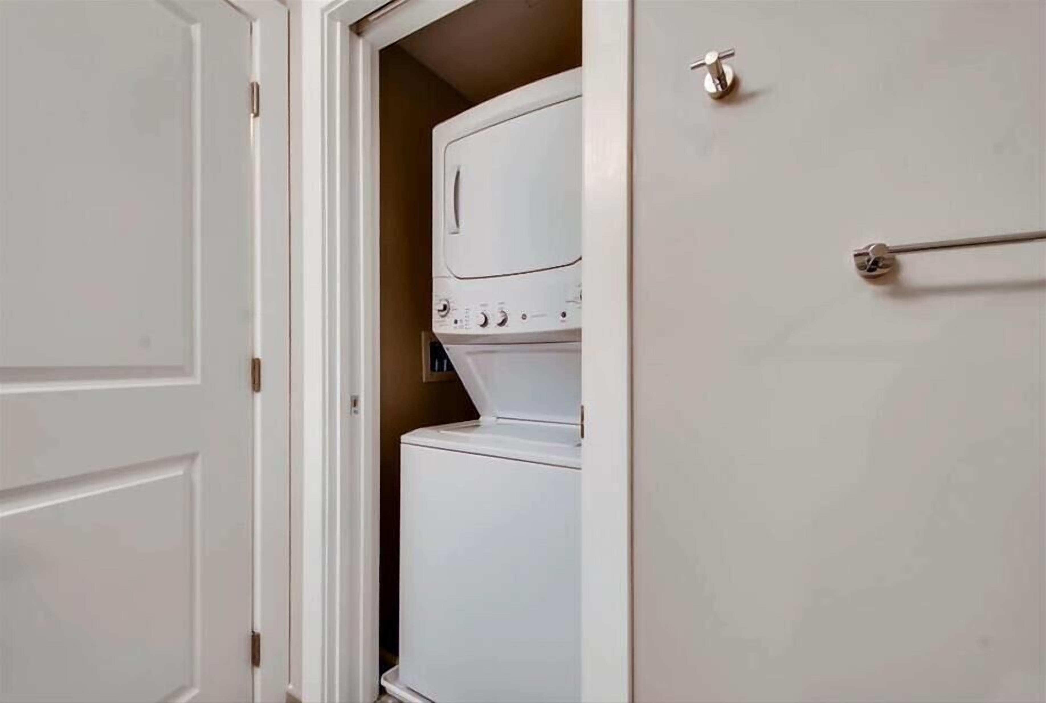 Un lavadero con lavadora y secadora de carga frontal, una puerta con picaporte plateado y un marco de puerta blanco.