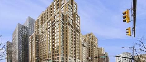 A high-rise building with a distinctive corner design, multiple floors, and a prominent entrance at street level.