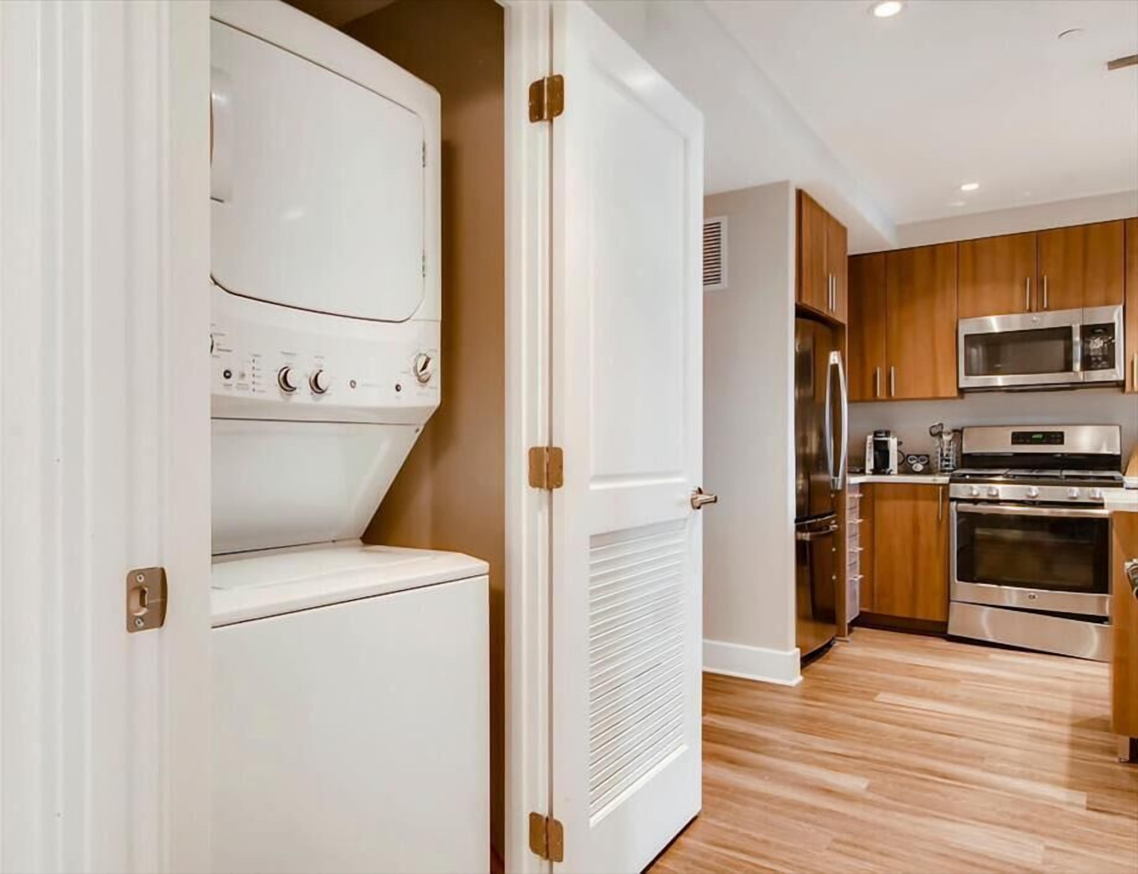 A modern kitchen with wooden cabinets, stainless steel appliances, and a built-in washer and dryer.