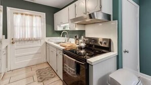 A compact kitchen with white cabinets, a stainless steel stove, and a small countertop. - Midcentury Charm by the Pond (Winston-Salem)