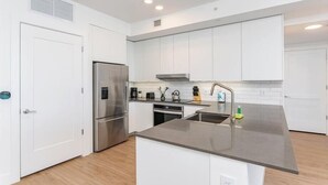 A modern kitchen with white cabinets, stainless steel appliances, and a grey countertop.