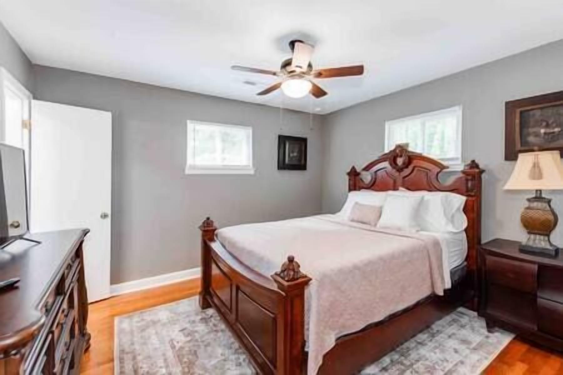A bedroom with a wooden bed, a ceiling fan, and a nightstand with a lamp.