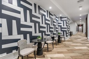 A modern hallway with geometric patterned walls, wooden flooring, and seating arrangements. - Near Hospitals 2 BR | Pet Friendly w Dog Run (White Plains)