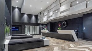 A modern reception area with a herringbone wood floor, dark walls, and a large digital display.