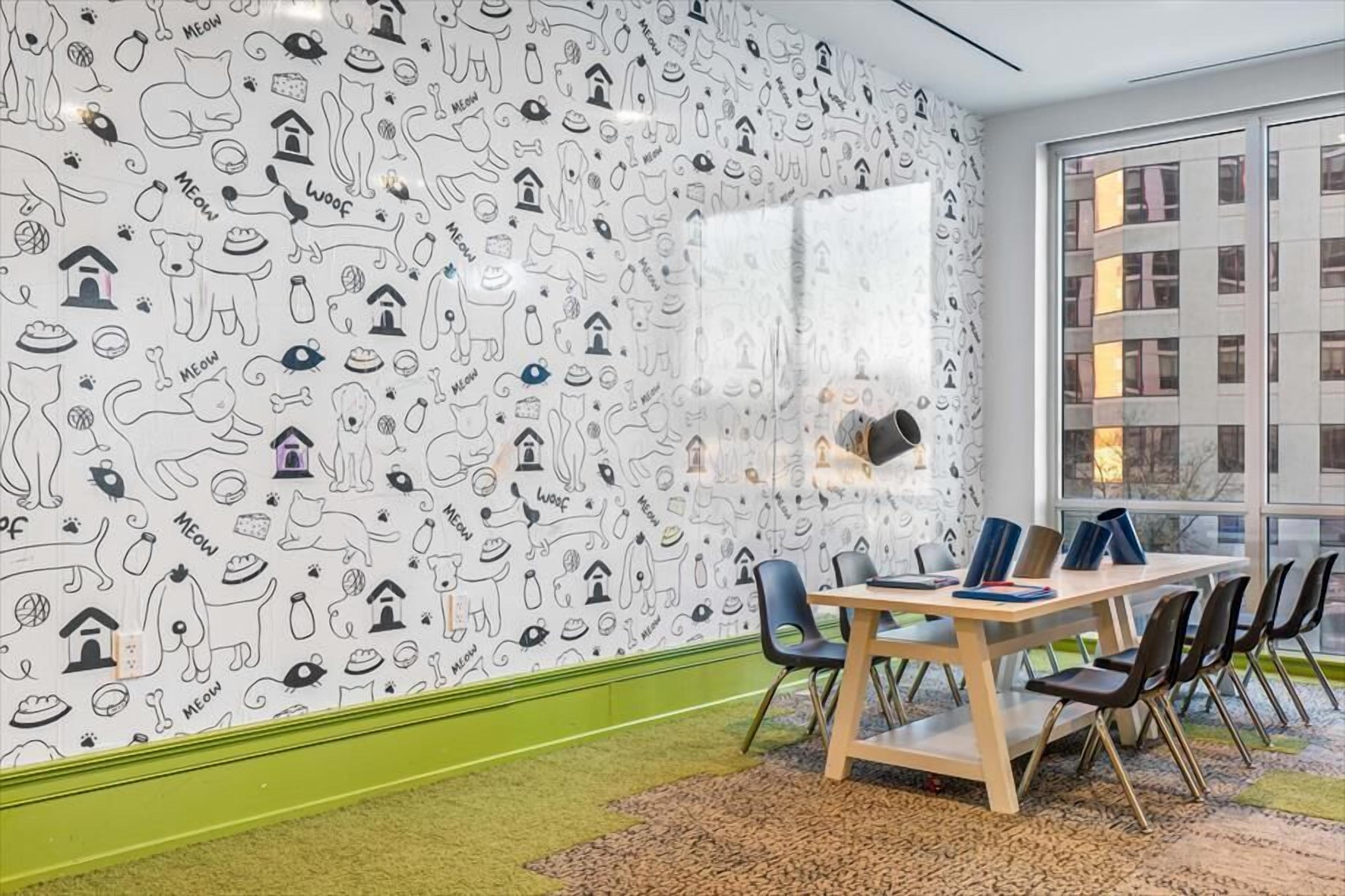 Una sala de reuniones con una pizarra, una mesa y sillas, y un papel tapiz decorado.