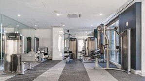 A modern gym with various exercise machines, a mirrored wall, and a carpeted floor.