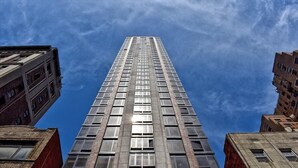 A tall, modern skyscraper with a glass facade and a central elevator shaft.