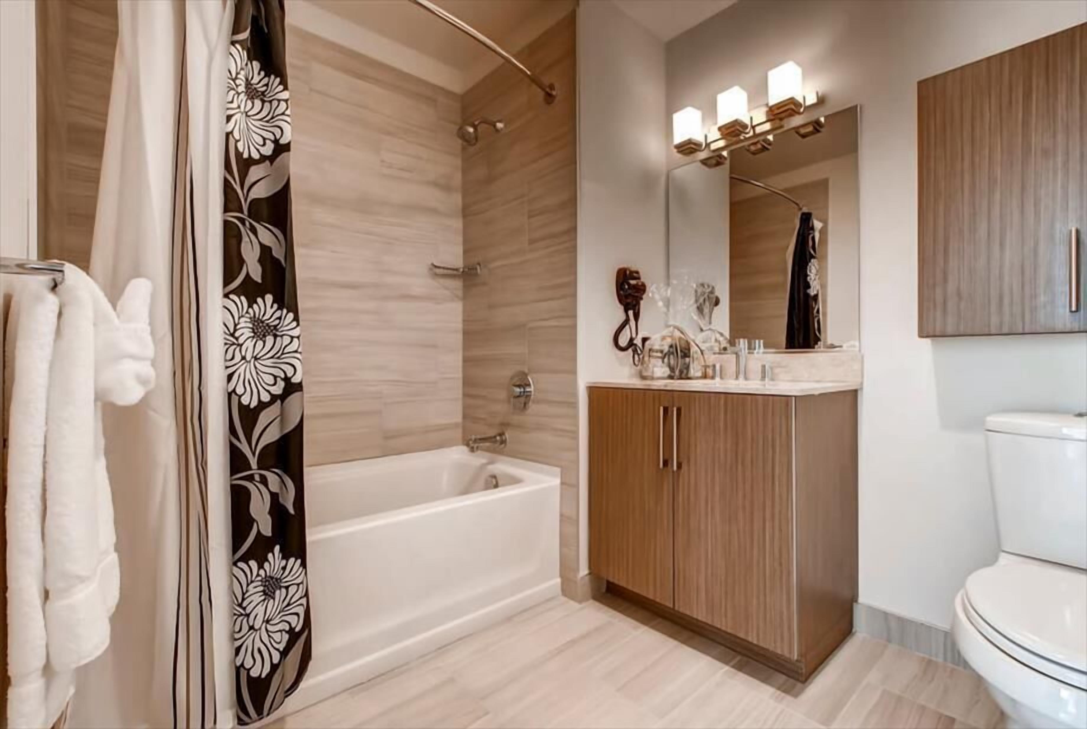 Ein modernes Badezimmer mit Badewanne, Holzschrank und Toilette.