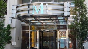 Un edificio moderno con un llamativo letrero con la letra 'M' sobre la entrada.