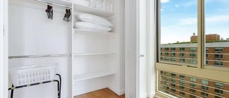 Una habitación con armario empotrado, ventana con vista a la ciudad y suelo de madera.