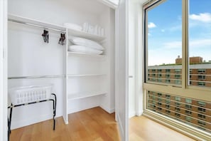 Quarto com armário embutido, janela com vista para a cidade e piso de madeira.