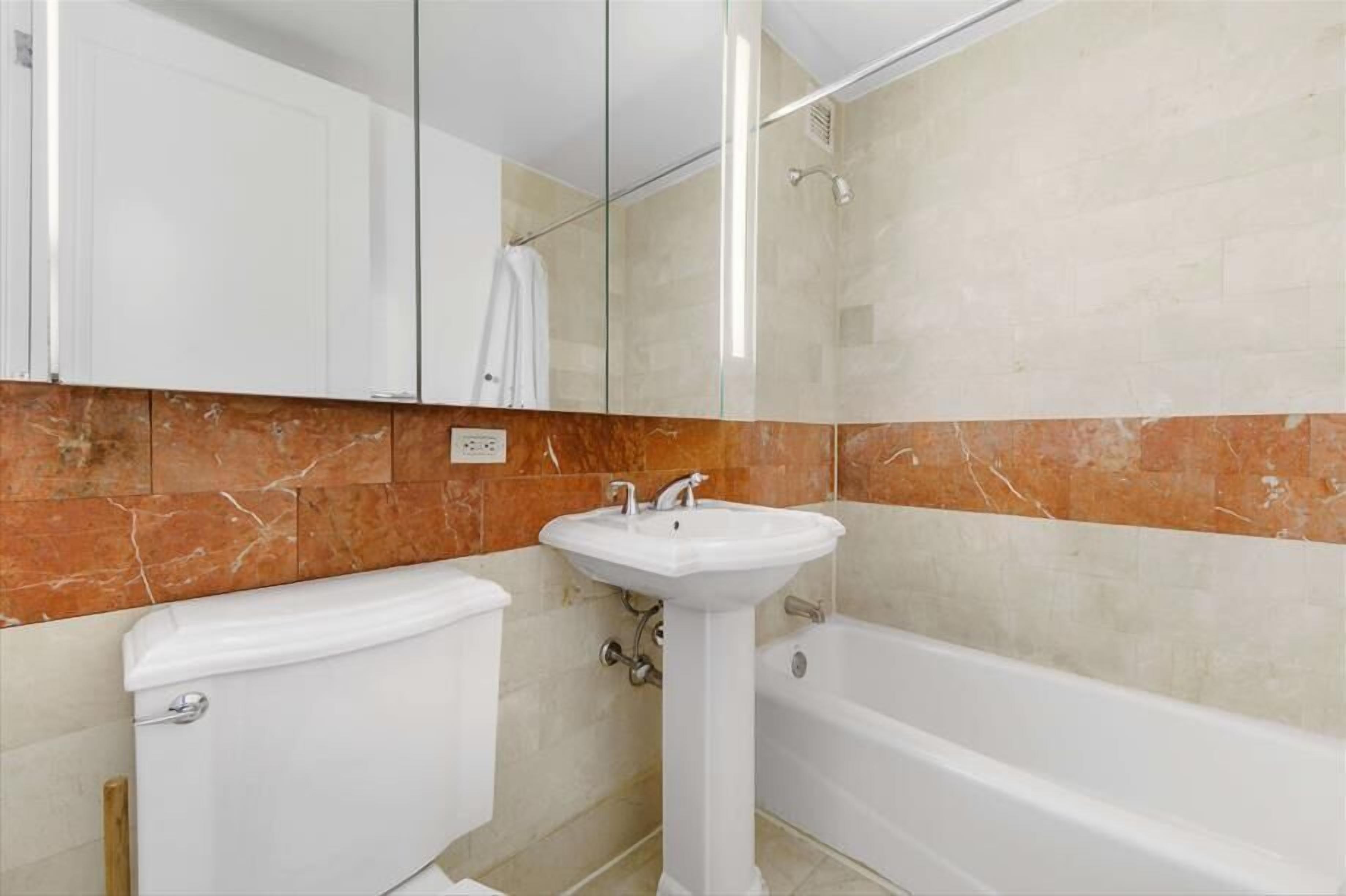 A bathroom with a white toilet, a pedestal sink, and a bathtub.