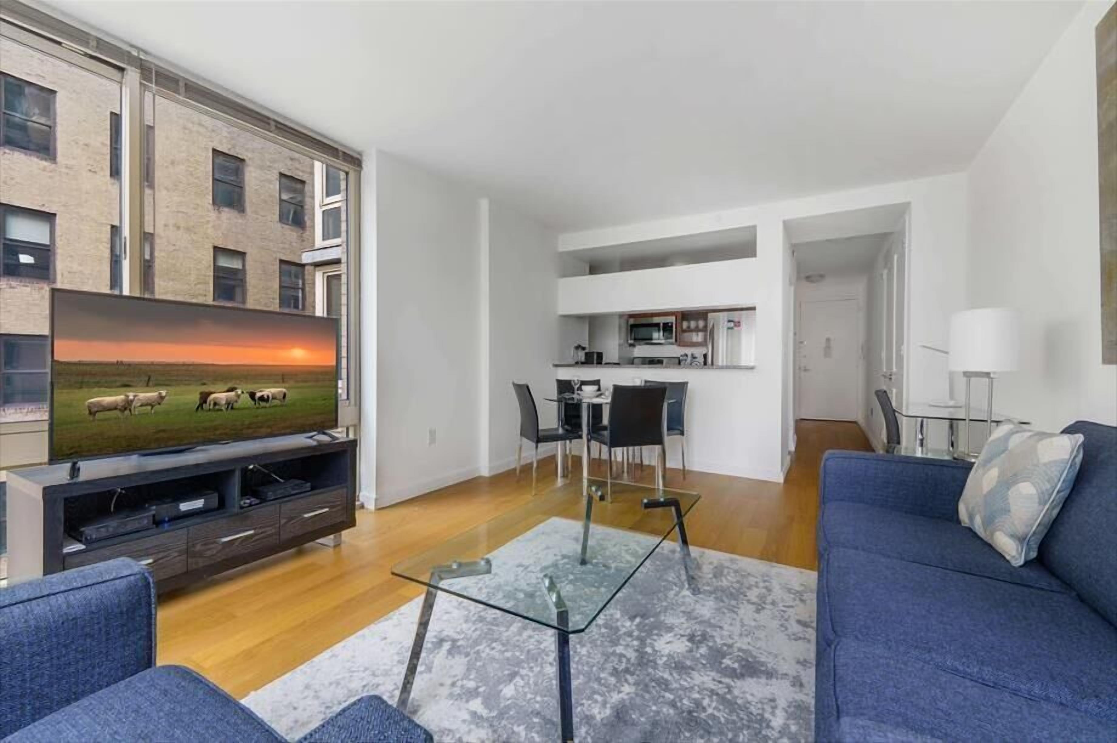 Um apartamento moderno com sala de estar equipada com televisão de tela plana, sofá e mesa de centro de vidro.