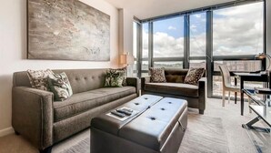 A modern living room with a large abstract painting, a sofa, a loveseat, and a coffee table.