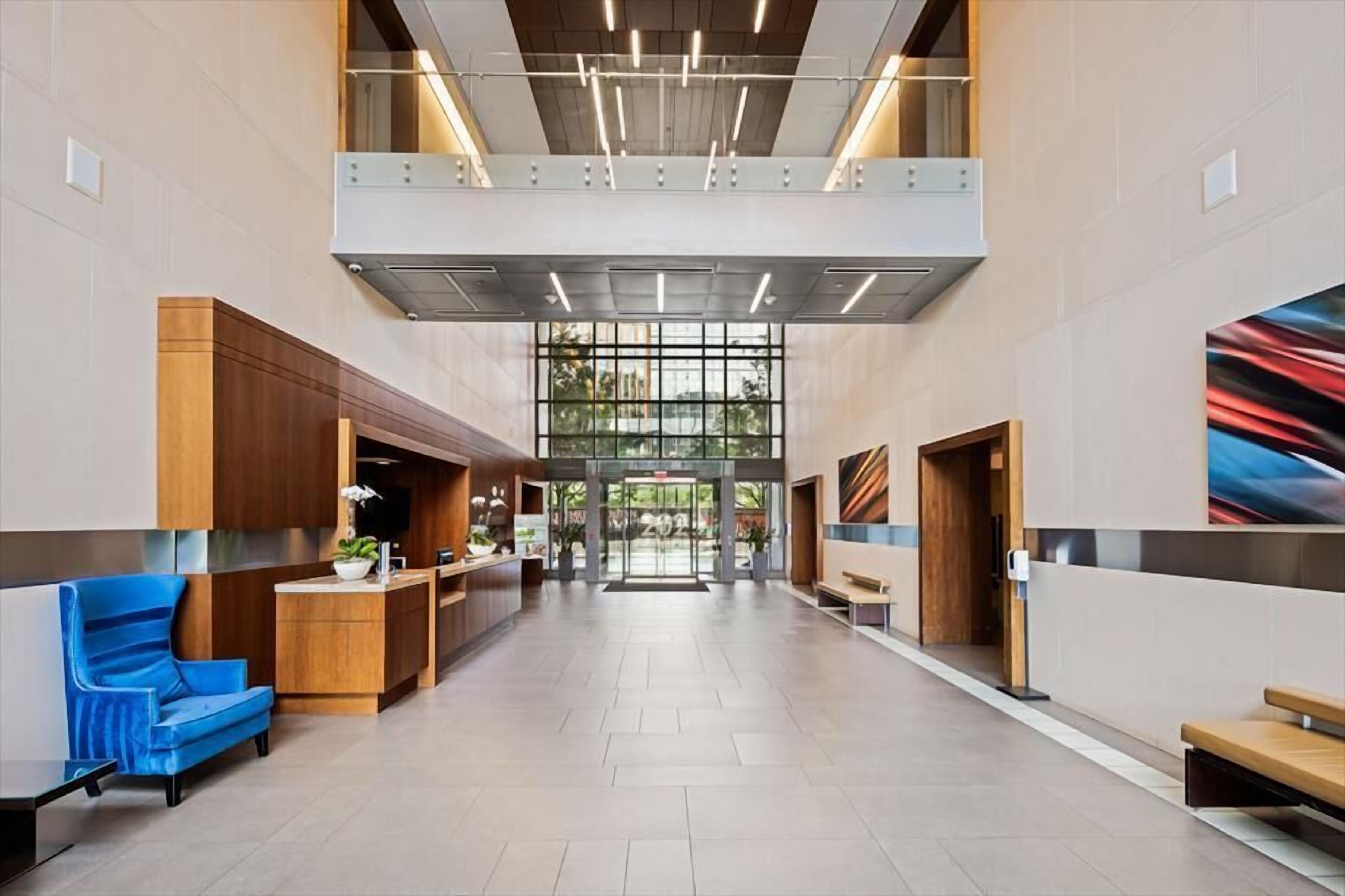 A spacious lobby with a reception desk, seating area, and a large glass entrance.