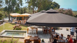 An outdoor patio area with tables and chairs, a pool, and umbrellas. - Akyaka Nehir Butik Otel (Ula)