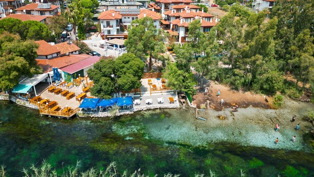 A coastal town with terraced houses, a waterfront bar, and clear waters. - Akyaka Nehir Butik Otel (Ula)