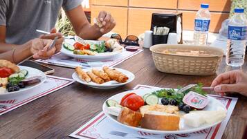 A wooden table with plates of food, a basket, and a water bottle.