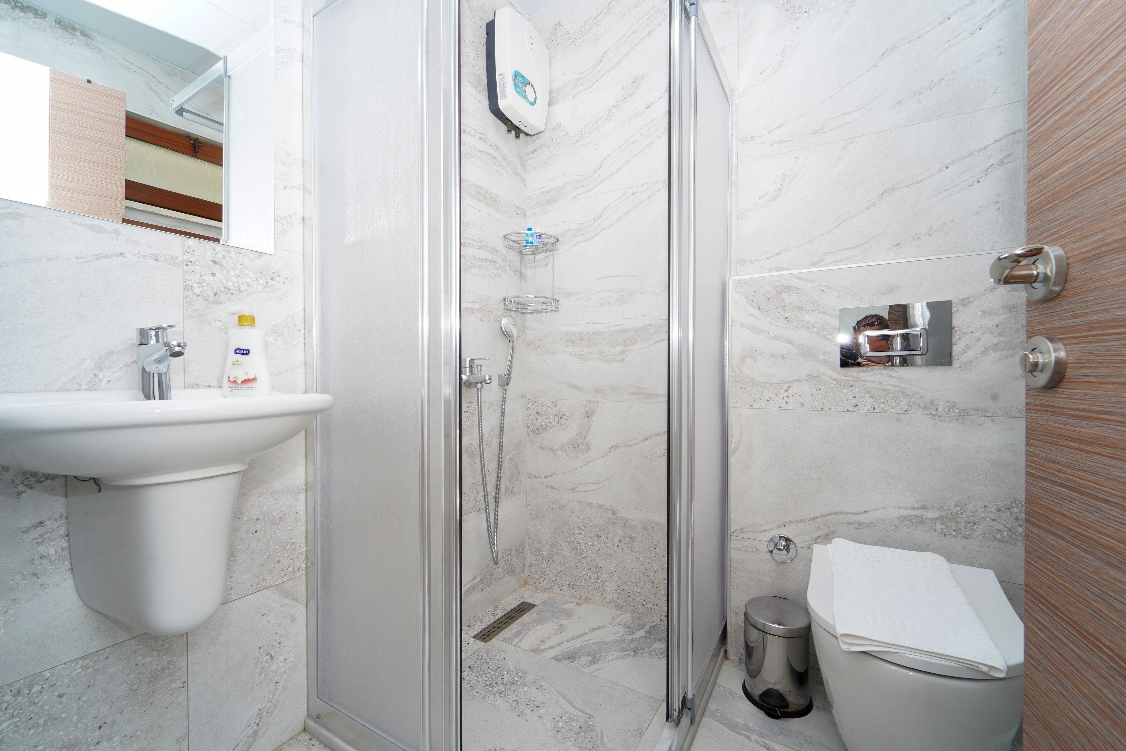 Un baño con ducha envuelta en vidrio, lavabo e inodoro.